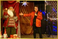 Weihnachtsbhne mit Weihnachtsmann und Ian mit Mikrofon.