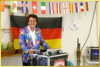 Schatzi IAN am Mischpult. Hinter ihm Deutschlandfahne und Länderwimpel zur Fußball-WM