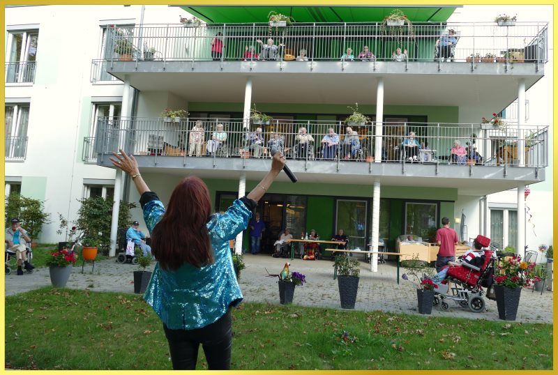 Marina winkt den Senioren auf den Balkonen zu.
