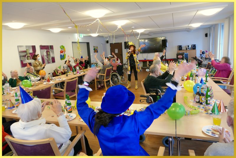 Tische in U-Form mit Senioren, die Karneval feiern.