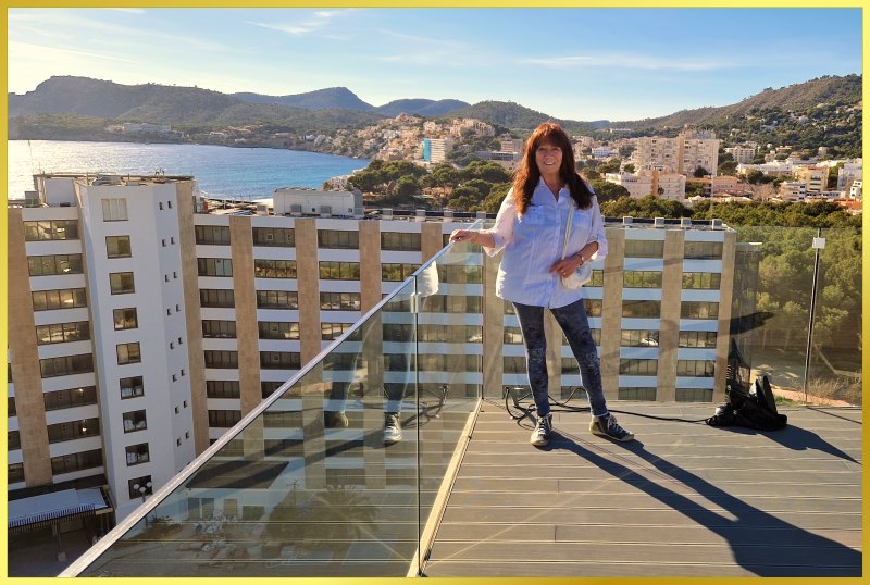Marina steht auf einem Dach auf Mallorca. Blick auf das Meer und Berge.