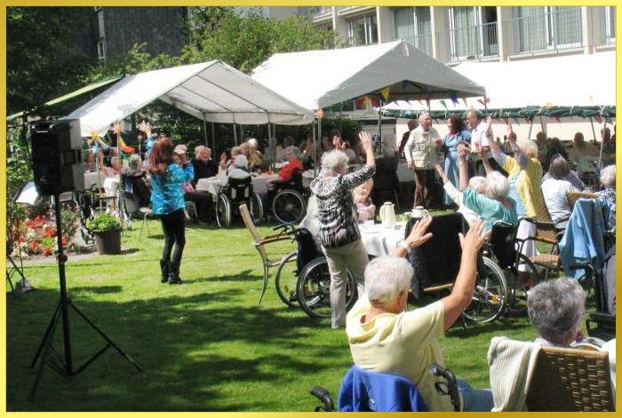 Groe Gartenanlage mit vielen feiernden Senioren beim Sommerfest. Schlagersngerin Marina singt.