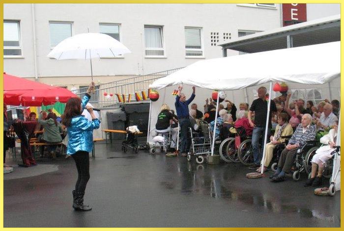 Schlagersngerin Marina singt frhlich mit Regenschirm in der Hand fr Senioren unter der Zeltberdachung.