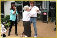 Marina und Ian singen zweistimmig einen bekannten Schlagerhit und eine Senioren tanzt mit Ian begeistert.